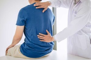 Person using a cold pack on the neck while seated at home after a vehicle accident.